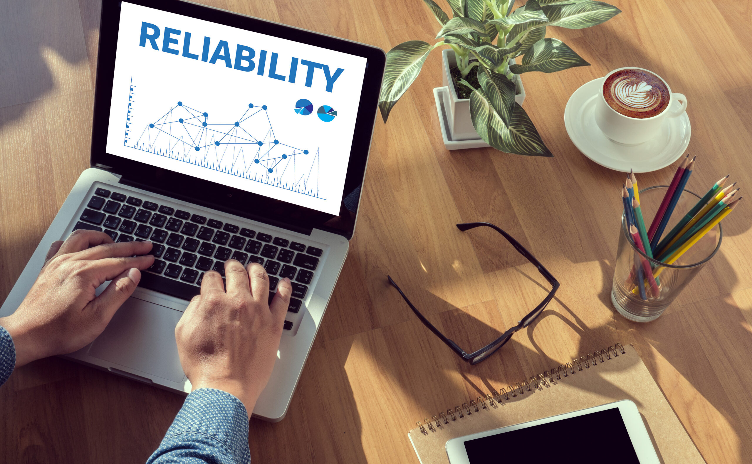 A laptop with a graph and the heading ‘Reliability’ written on it on an office desk referring to how reliability needs to be measured or evaluated.