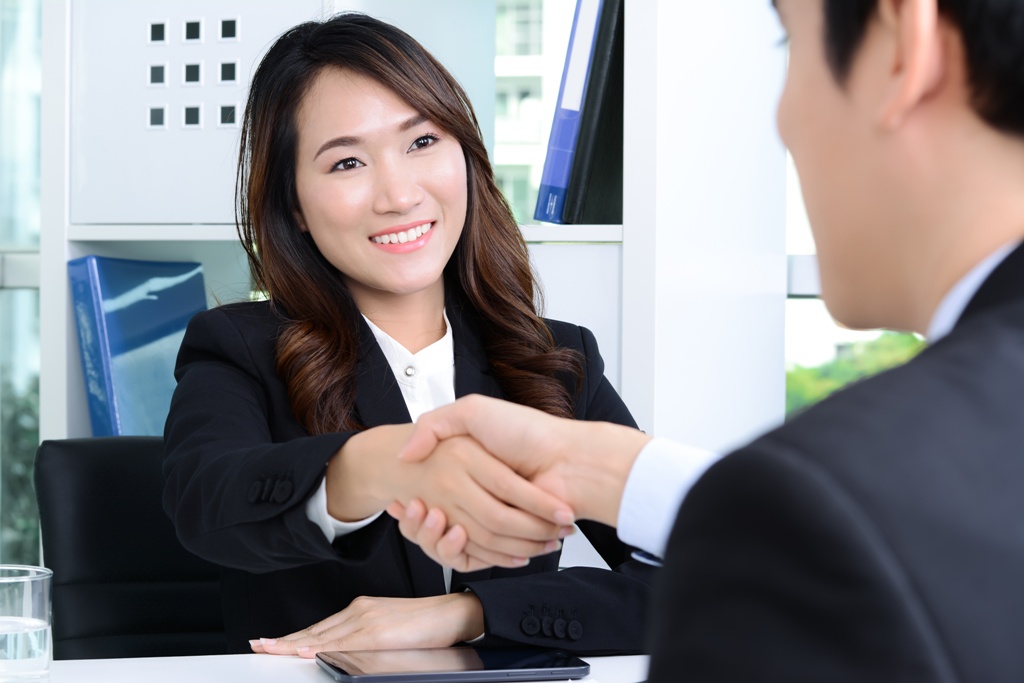 A woman at an office desk shaking hands with a man signifying a reliable moneylender loan agent in Singapore