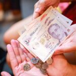 One person giving and another receiving cash to indicate an urgent cash loan in Singapore