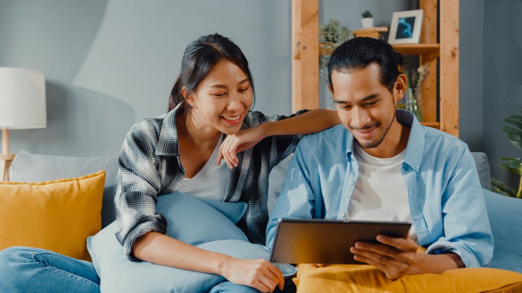 A young smiling couple evaluating online lending services on their tablet