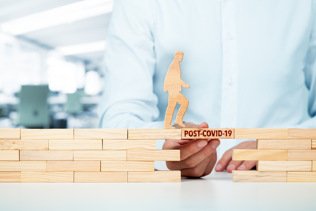 Representation of man applying for loan pwalking across wooden block with post-covid-19