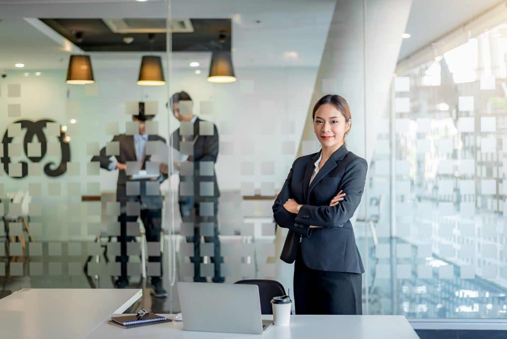 Young businesswoman in an office looking confidently into the camera with businessmen in the background