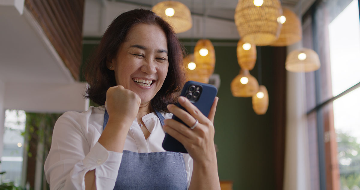 Thrilled mature lady grinning at her cellphone, happy that her loan from a private moneylender's approved 