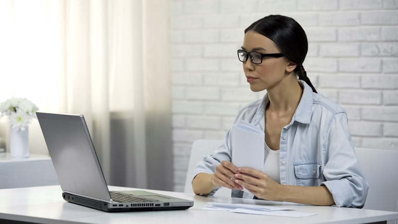 Woman looking at a laptop screen and considering to get a personal loan with bad credit