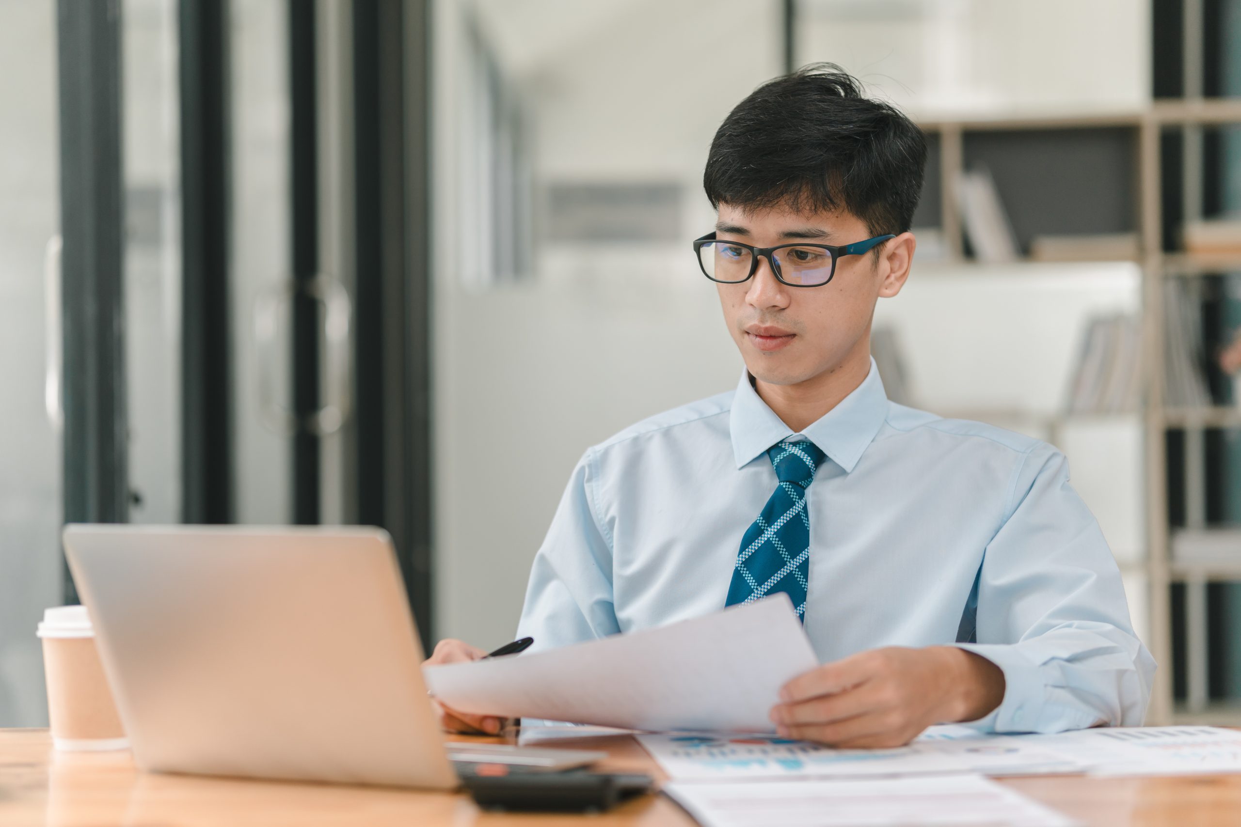 An asian man with glasses reviewing his instant loan application online