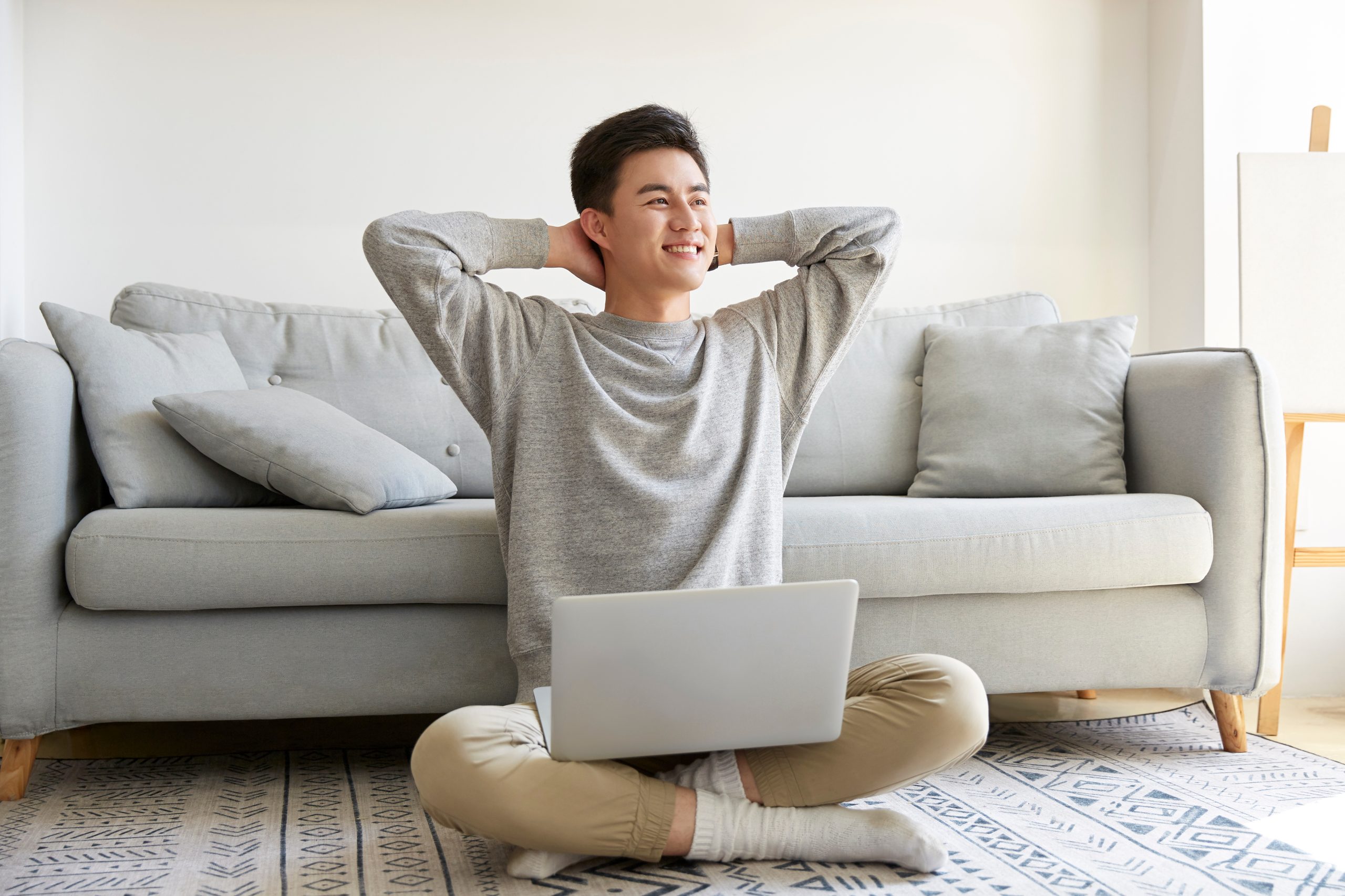 happy man sitting at home with a laptop who just got a personal loan in Singapore