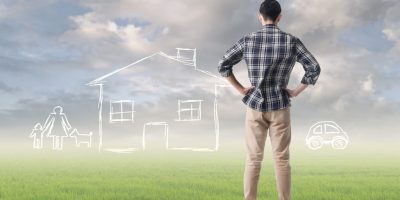 A man looking out at an open space that has chalk drawings of a family, house, and car, representing a person who has personal goals and dreams and wants to apply for a loan.