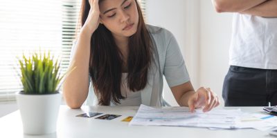 A worried looking woman staring at her bills to indicate that she needs fast cash.
