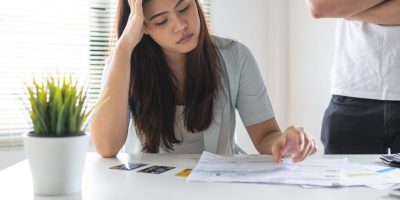 A worried looking woman staring at her bills to indicate that she needs fast cash.