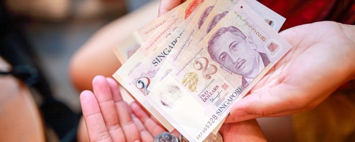 One person giving and another receiving cash to indicate an urgent cash loan in Singapore