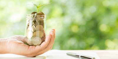 woman-hand-holding-plant-growing-from-coins-bottle